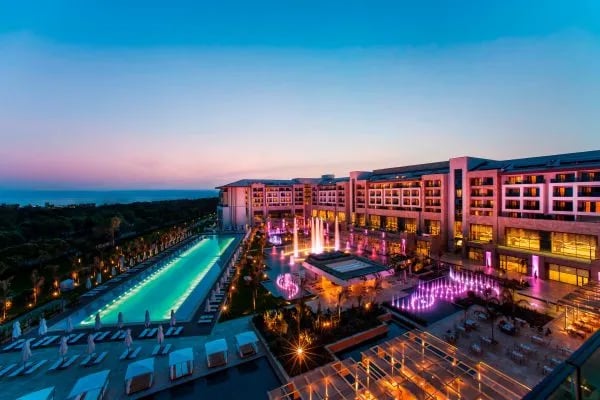 Akşam ışıklarında lüks resortun havuz aksı ve blokları, havadan